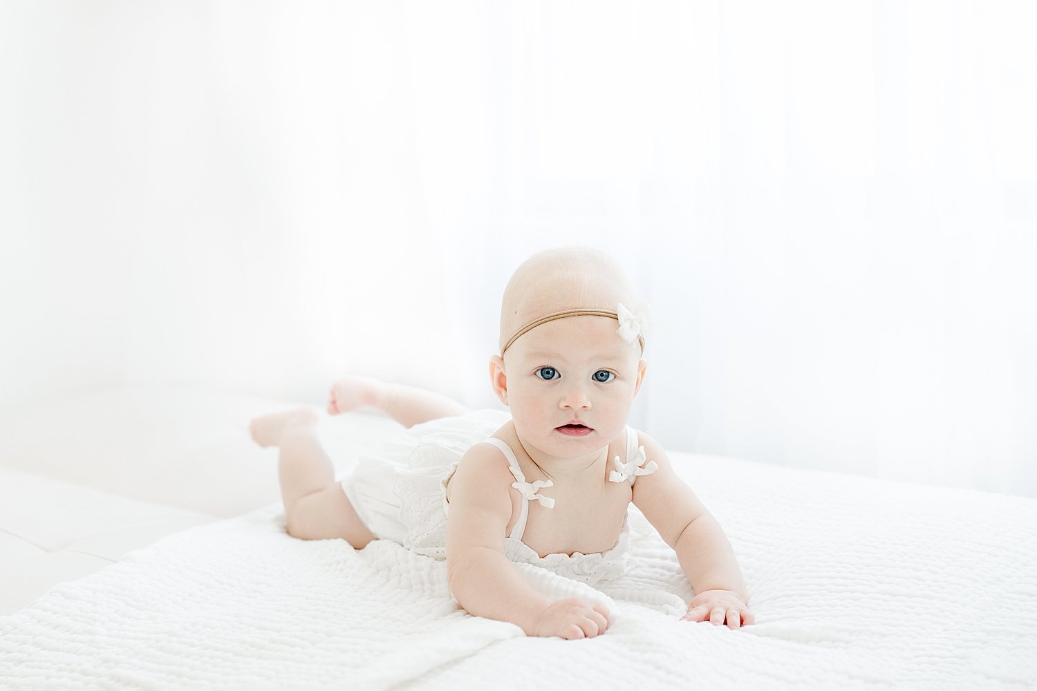 Baby girl on bed for milestone session at eight months with Kristin Wood Photography.