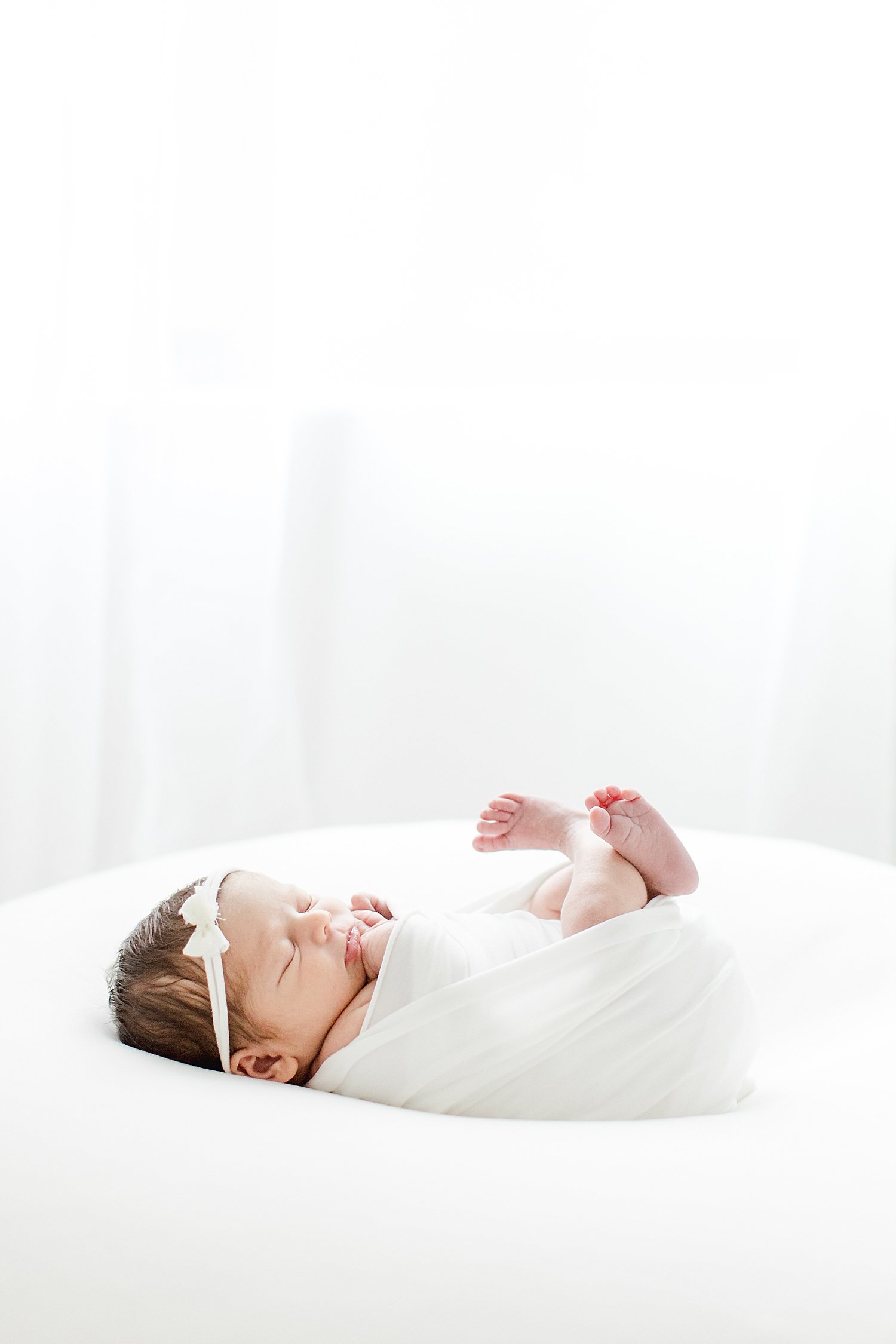 Baby girl swaddled in white for newborn photos with Kristin Wood Photography.