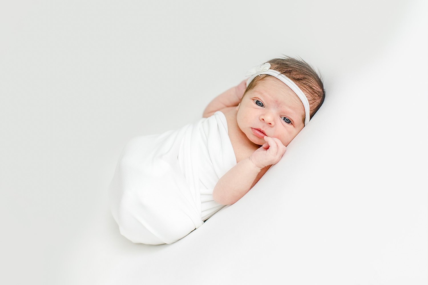 Baby girl swaddled in white for newborn photos with Kristin Wood Photography.Newborn baby girl awake during photoshoot | Kristin Wood Photography