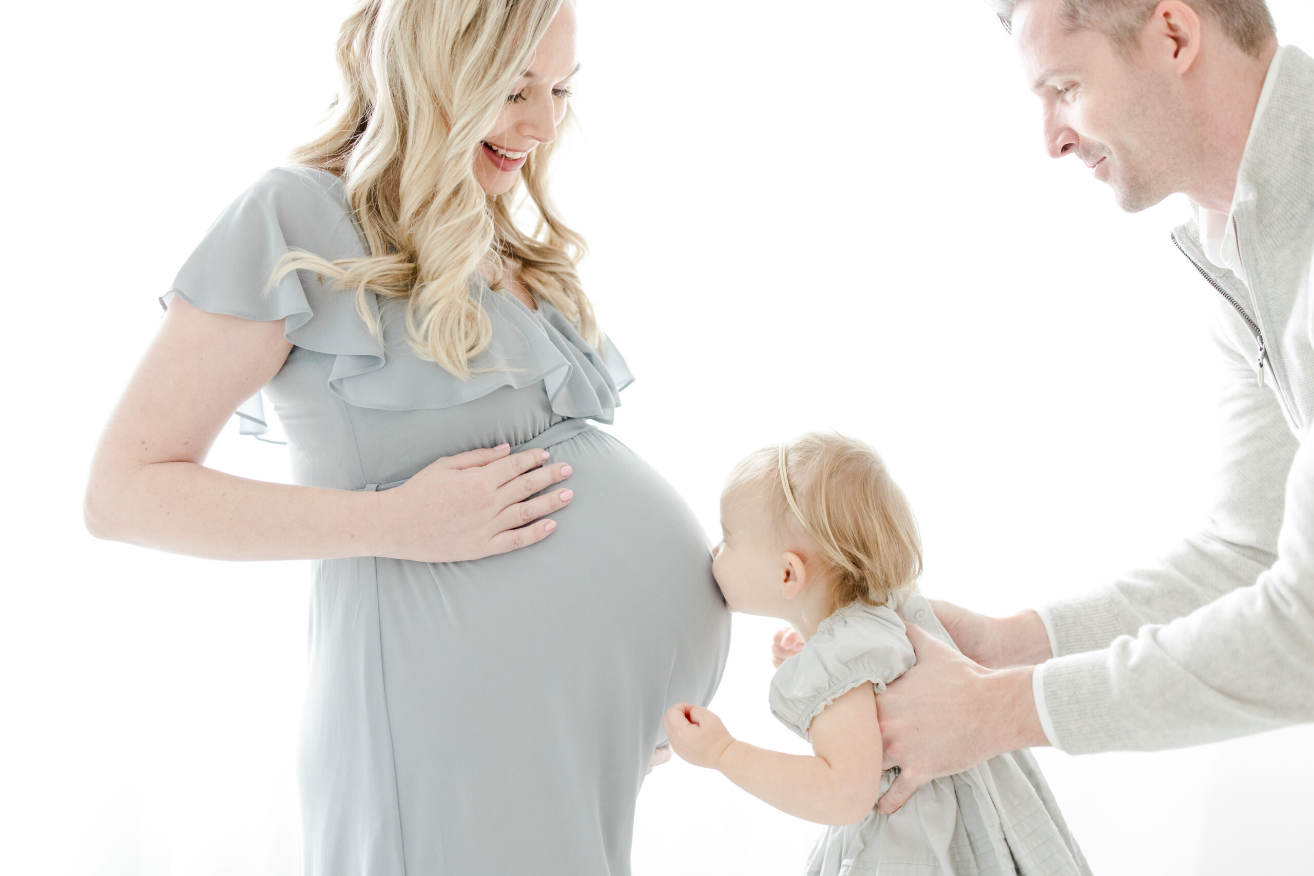 What To Wear for Your Maternity Session | Dad holding daughter up to Mom's pregnant belly giving her a kiss | Kristin Wood Photography