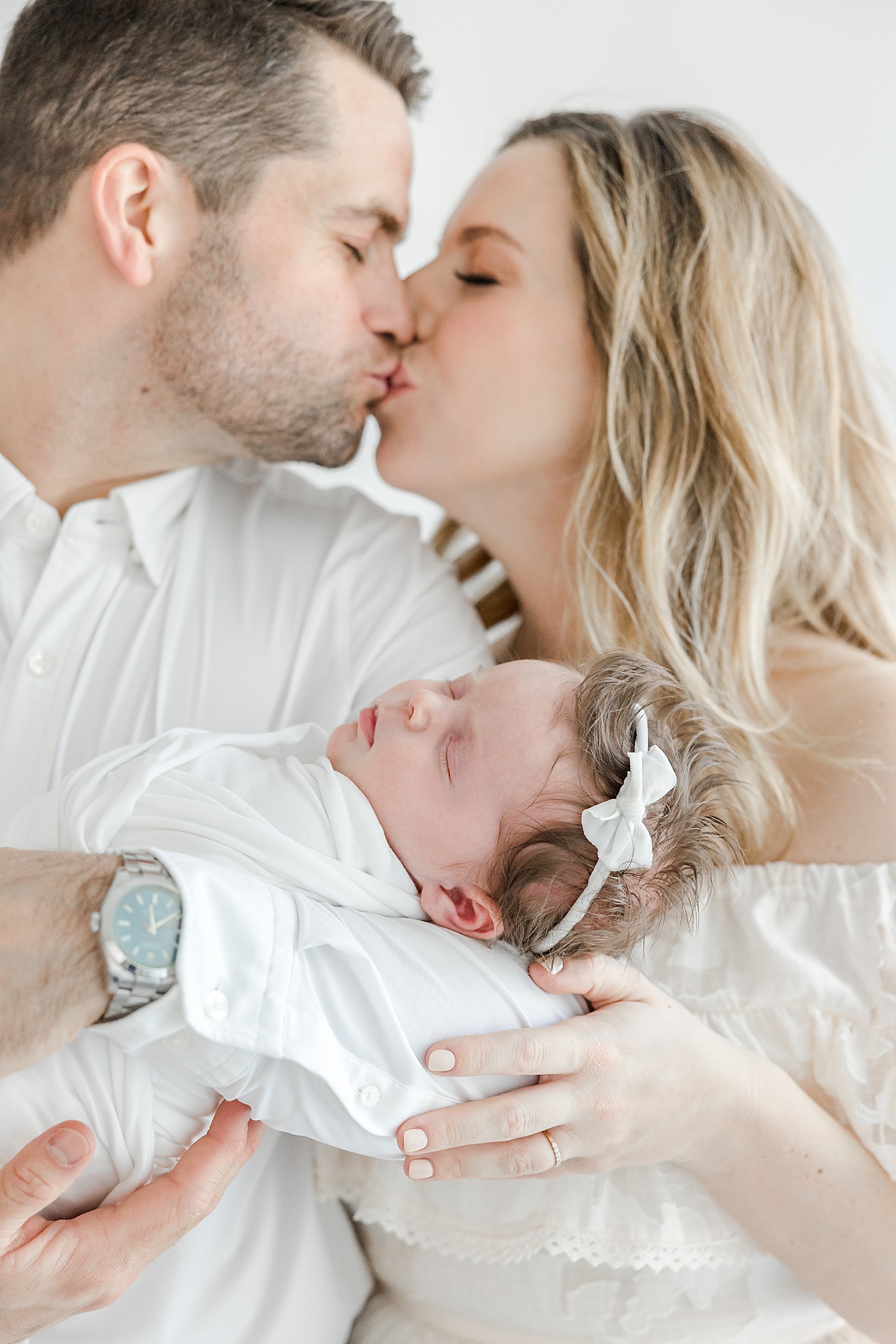 Parents kissing while holding newborn daughter | Kristin Wood Photography