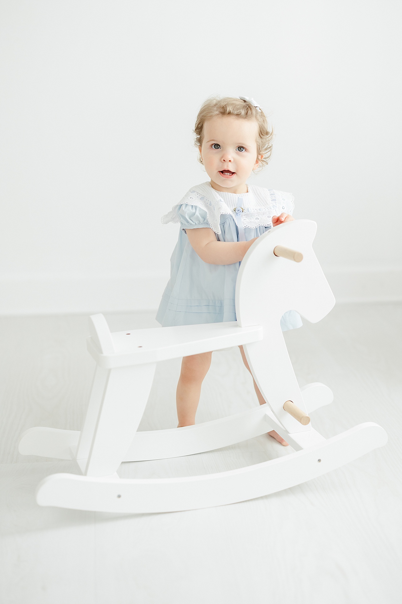 One year old riding a rocking horse during first birthday photoshoot with Kristin Wood Photography.