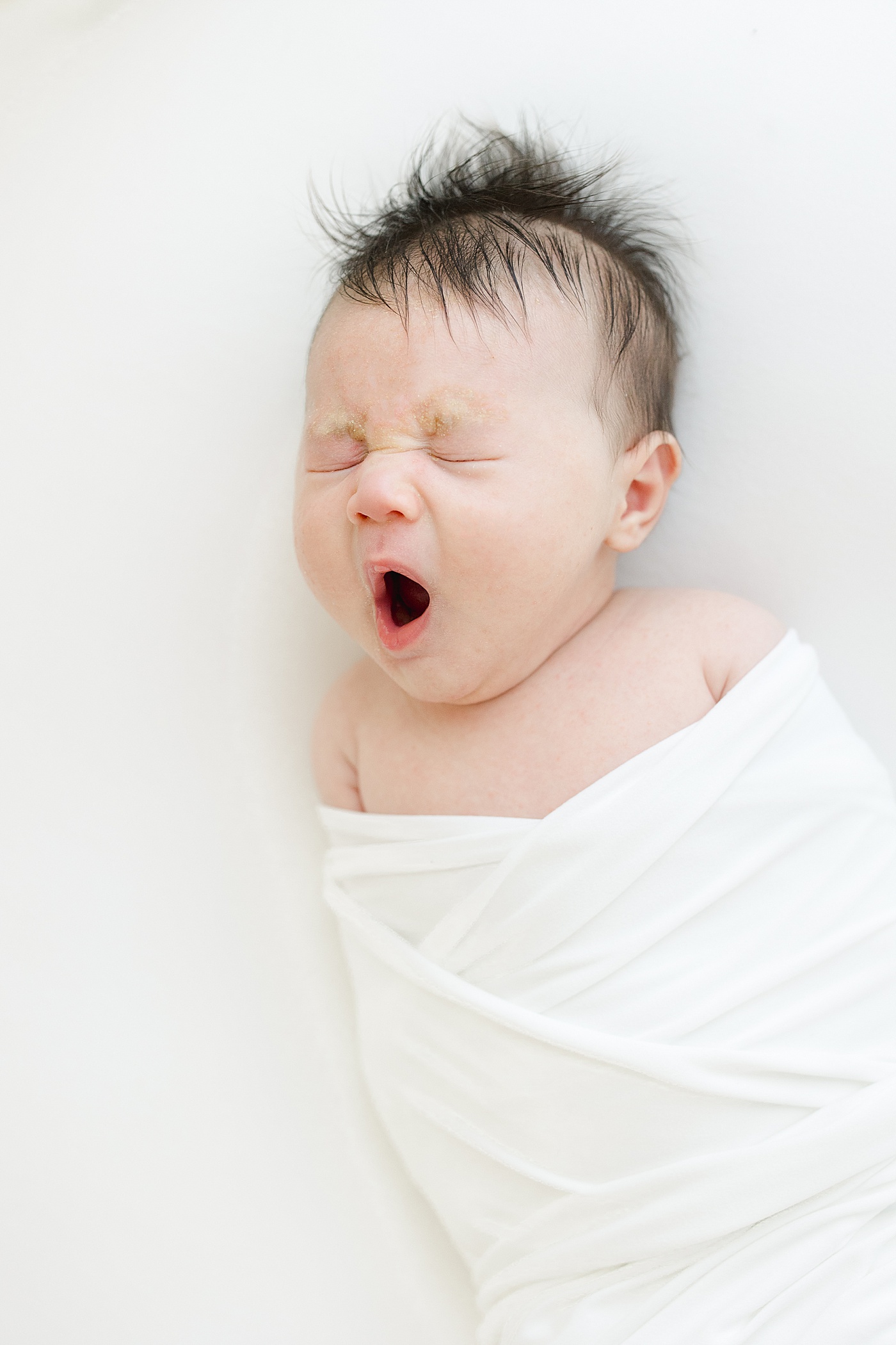 Newborn baby boy yawning during photoshoot with Kristin Wood Photography.