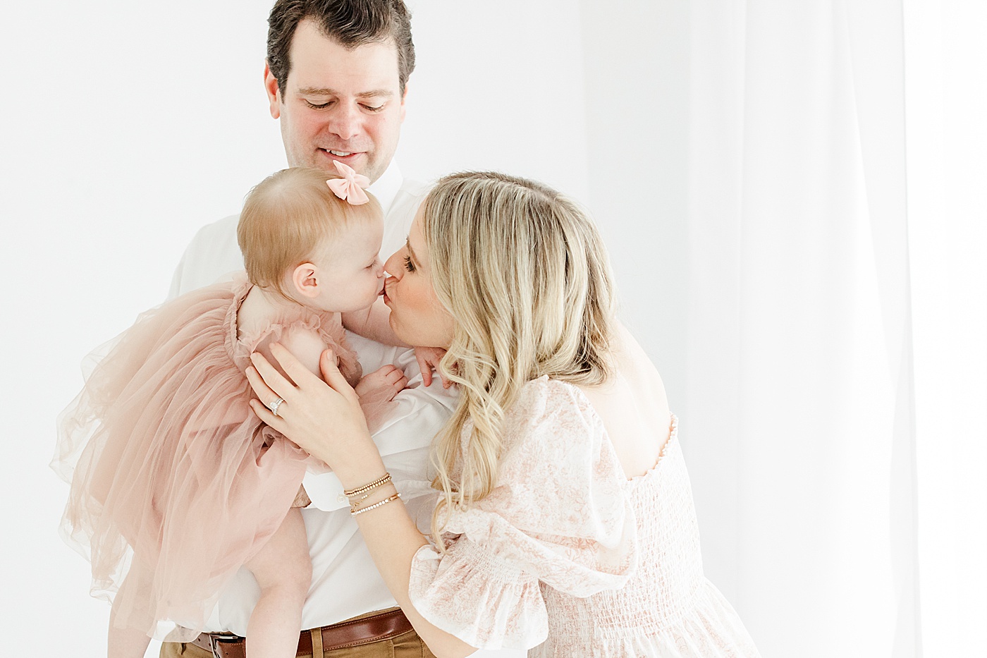 Mom kissing daughter during first birthday photoshoot | Kristin Wood Photography
