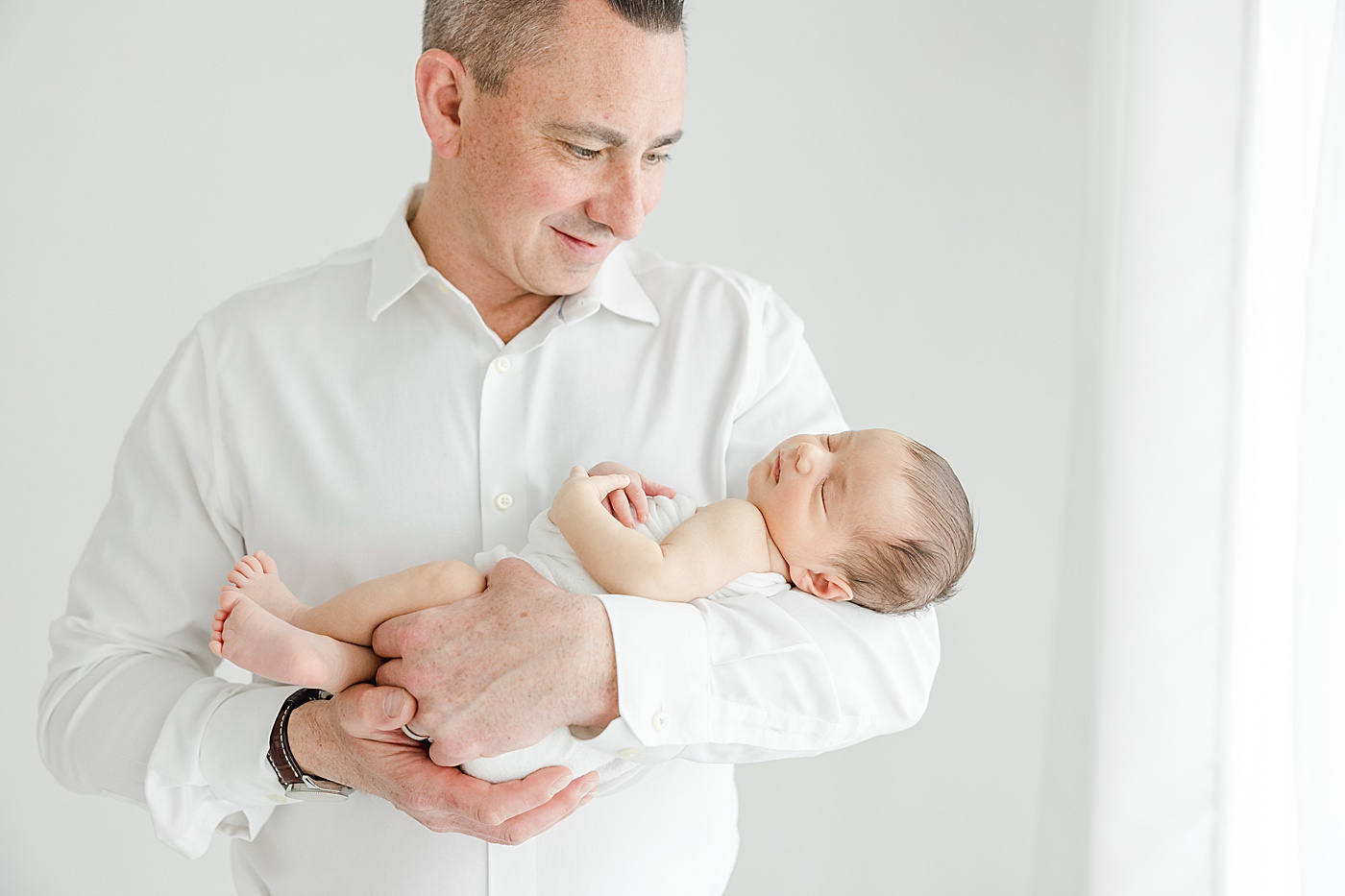 Dad holding son during newborn photos with Kristin Wood Photography in Westport studio.