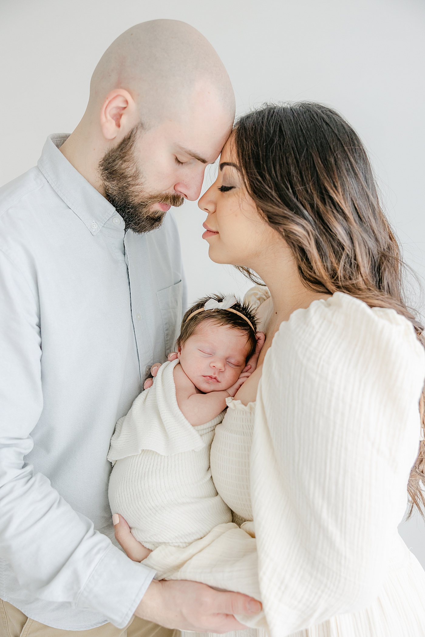 Mom and Dad share sweet moment while holding baby girl during newborn photos with Kristin Wood Photography.