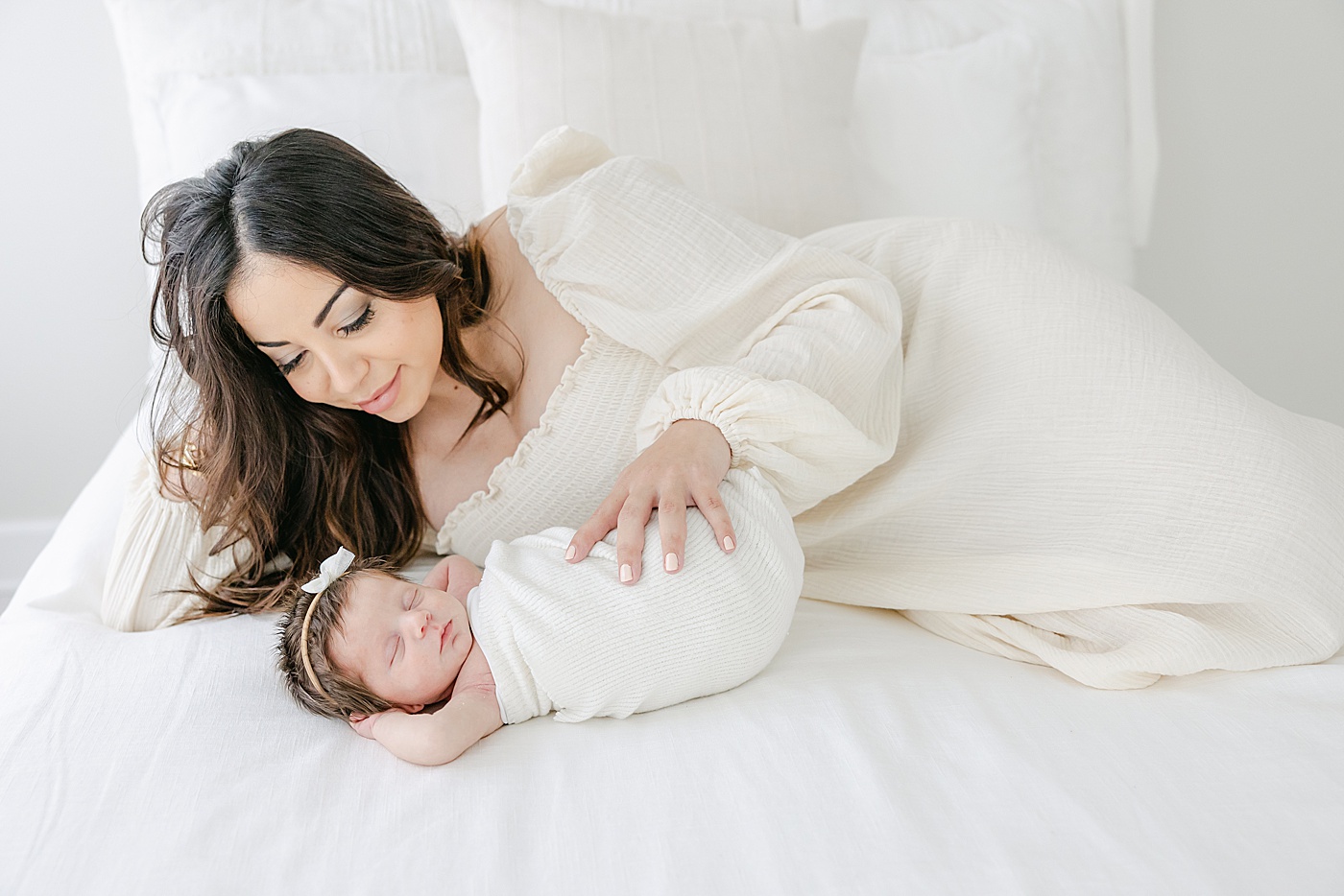 Mom laying on bed with newborn daughter | Kristin Wood Photography