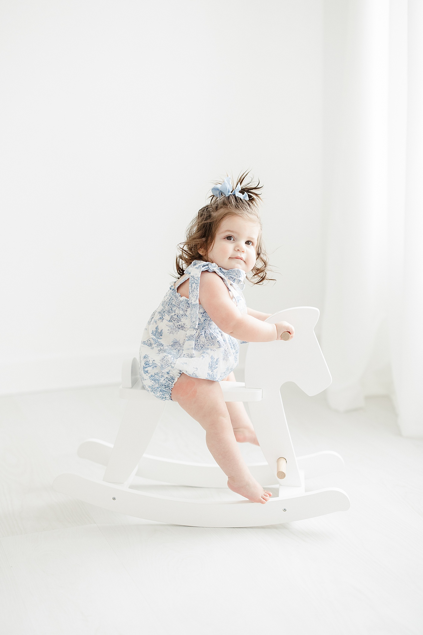 One year old sitting on rocking horse during first birthday photoshoot | Kristin Wood Photography