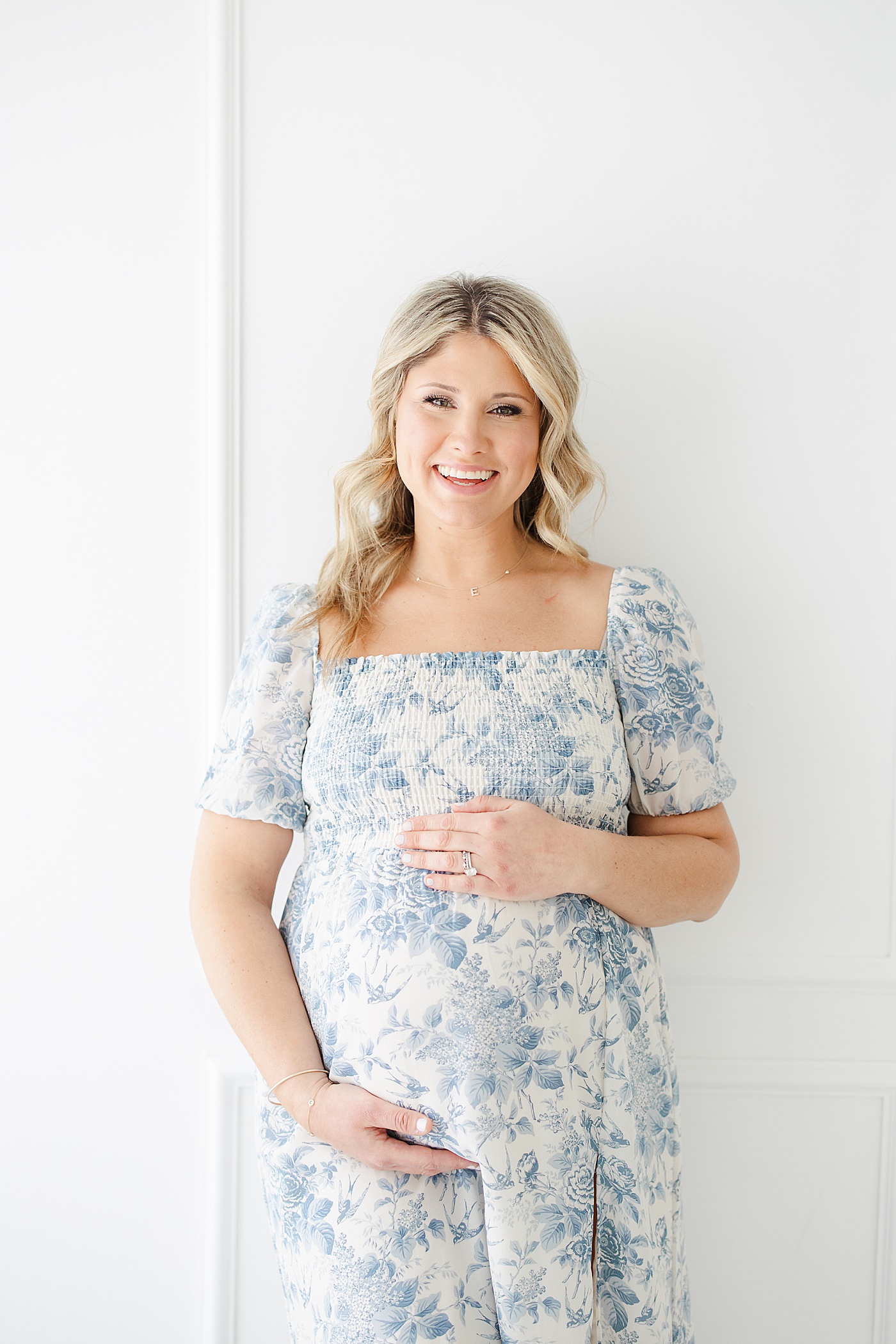 Expecting mom wearing a blue floral dress for maternity photos in studio with Kristin Wood Photography.