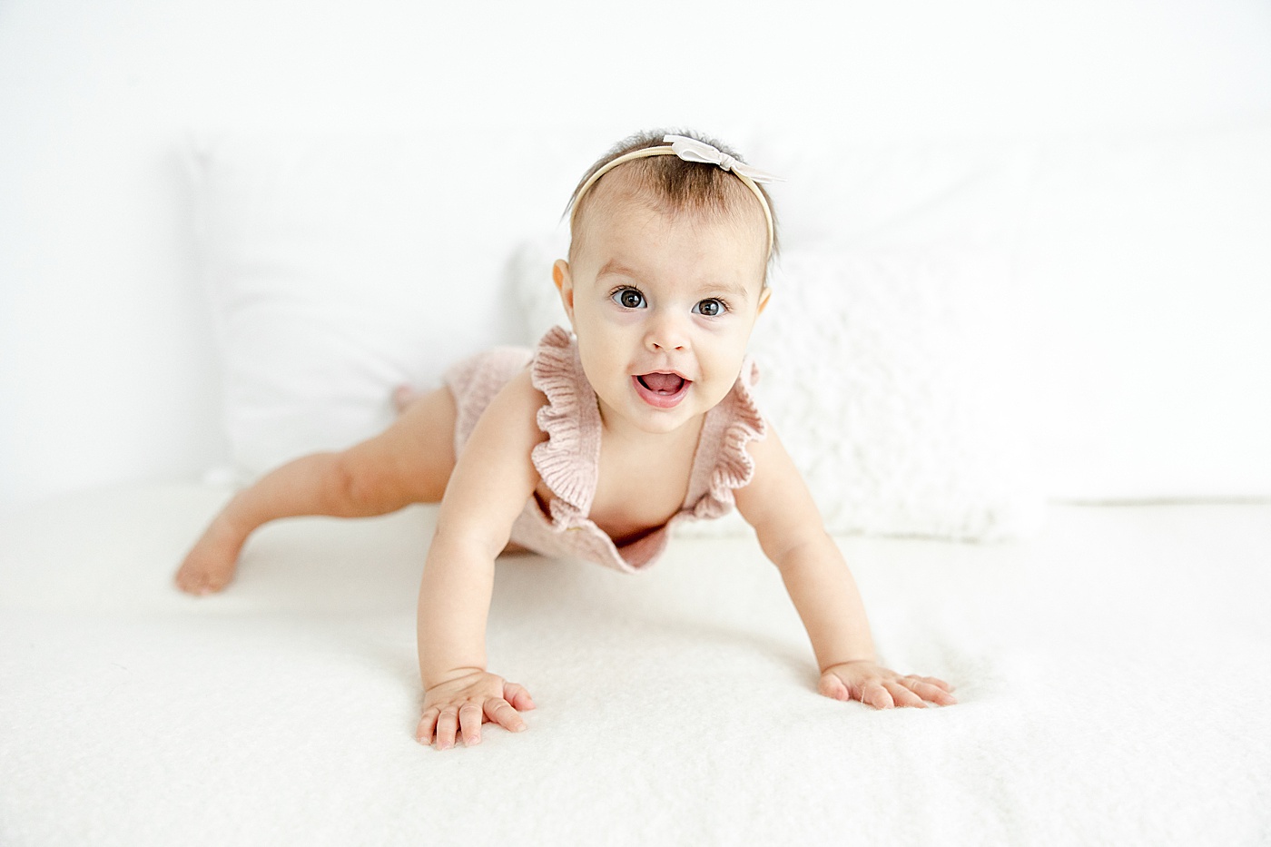 8 month old pushing up on bed during milestone photoshoot with Kristin Wood Photography.